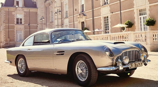 a classic aston martin in front of mansion